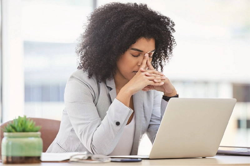 business black woman at work using a laptop while suffering from a headache